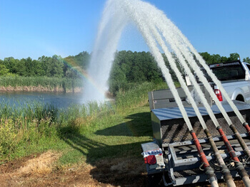 View of truck inspecting fire pump fed by pond 